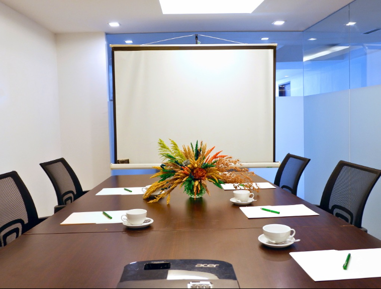A meeting room with a table and chairs and a projector screen at a hotel in cabanatuan