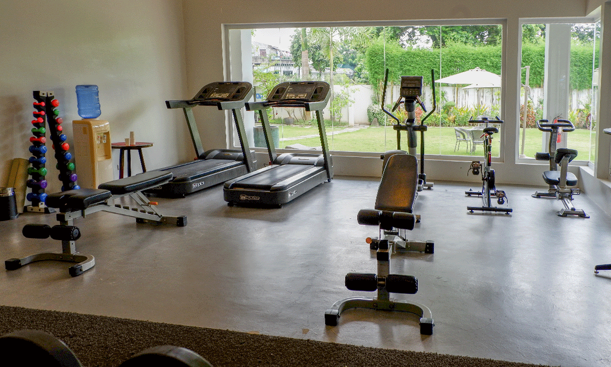 Fitness gym with treadmills , exercise bikes , dumbbells and a bench in the Hotel