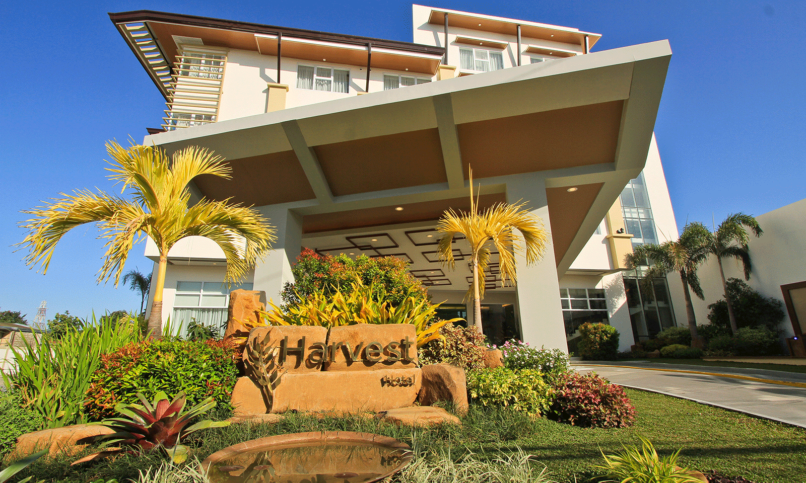 The modern exterior of Harvest Hotel at dusk, the premier hotel in Cabanatuan for leisure and business accommodation.