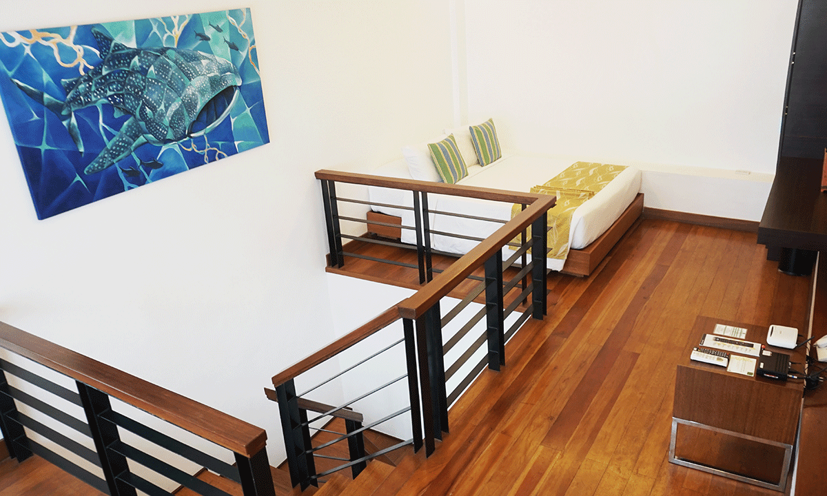 A staircase leading up to a bedroom with a bed and a painting on the wall.