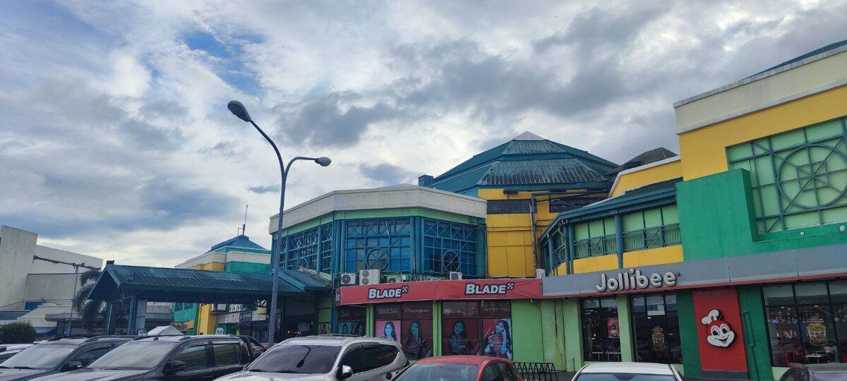 A colorful building with a blue dome under a cloudy sky. A Jollibee restaurant is visible.