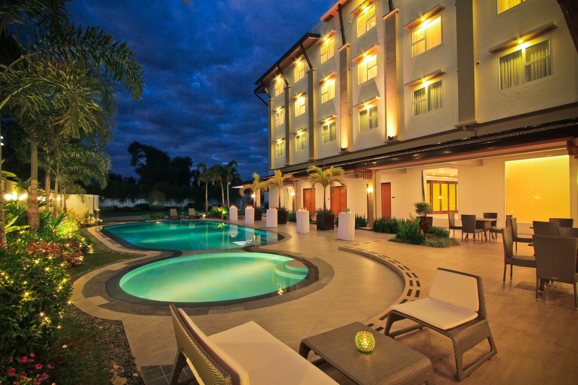 Harvest Hotel outdoor pool at night with lush tropical gardens, Cabanatuan 