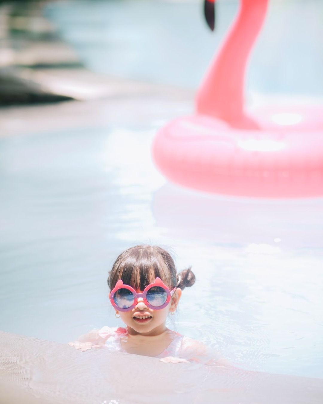 A kid is swimming in a pool with a pink flamingo float at a family hotel in cabanatuan