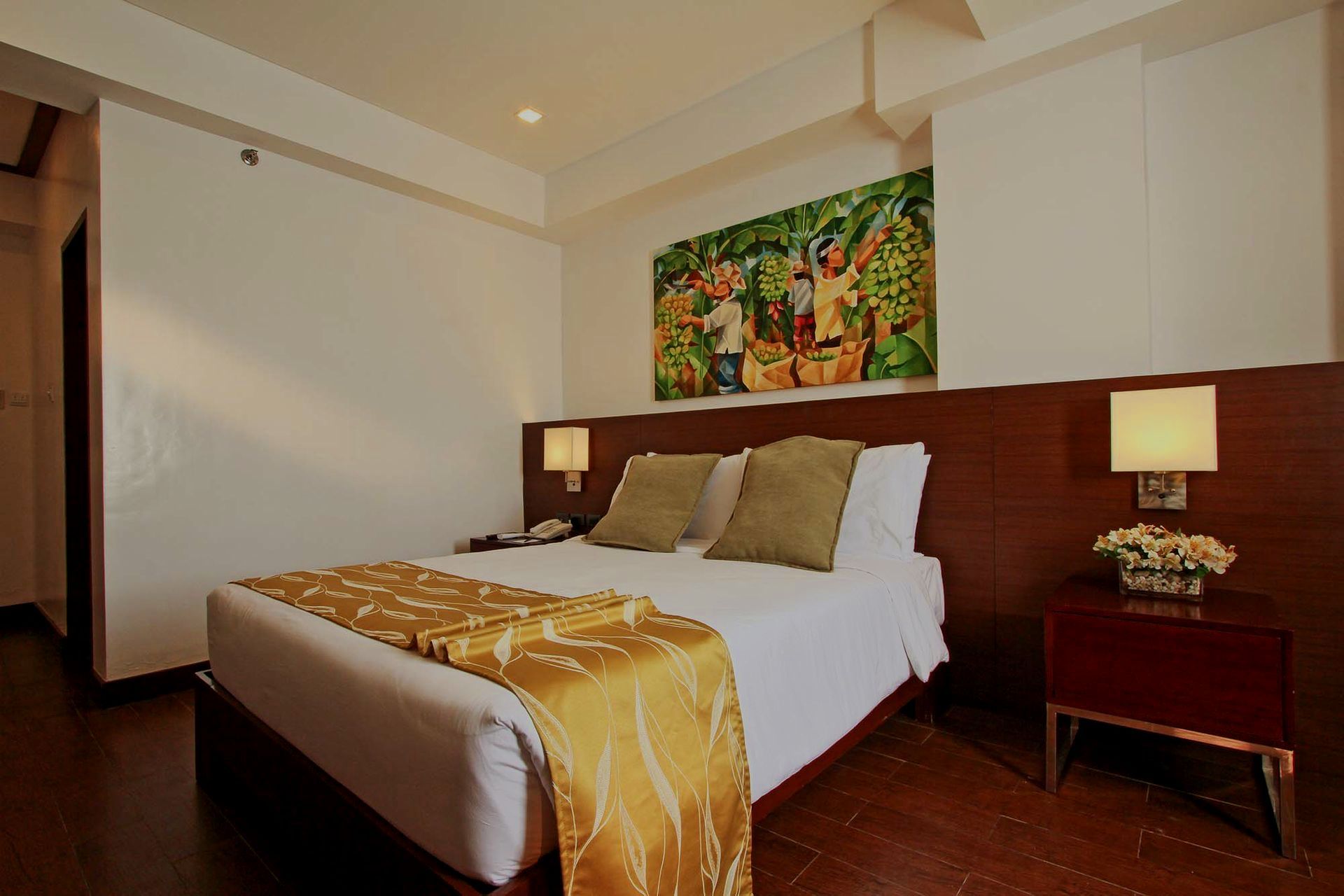 Hotel bedroom with a bed, artwork, and nightstands.