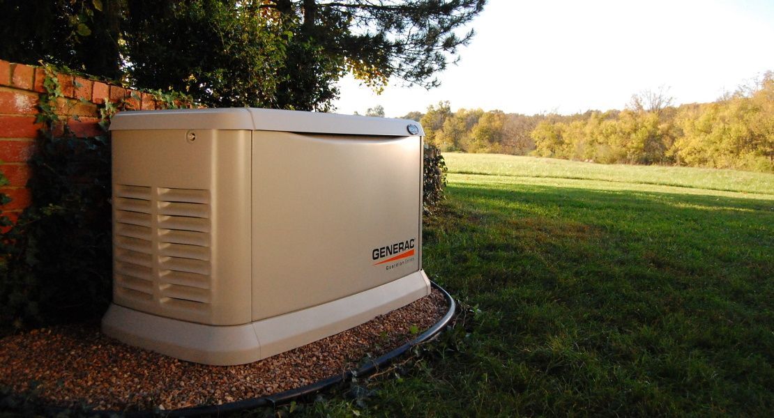 a Generac generator is sitting in the grass next to a brick wall .