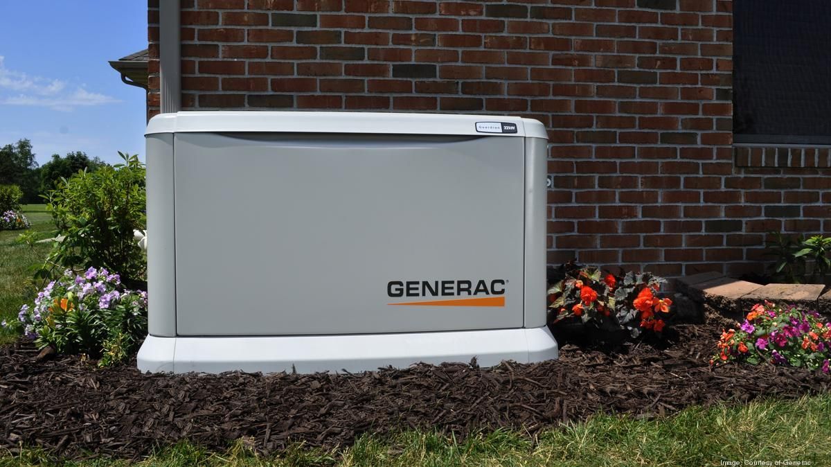 a generac generator is sitting in front of a brick house .