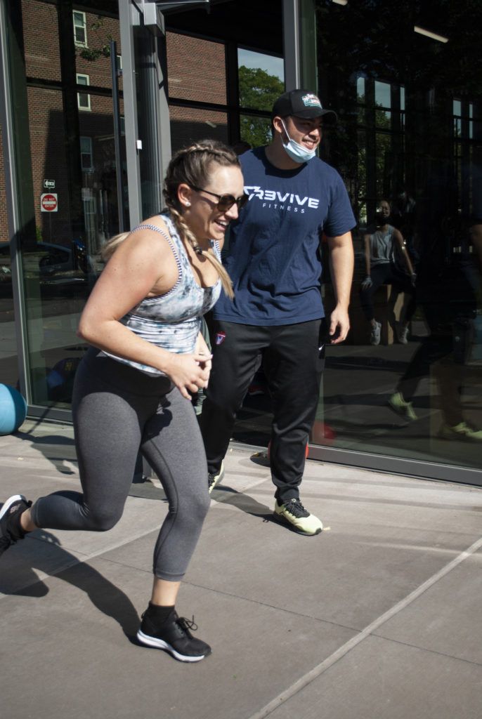 An athlete having fun running and her coach encouraging her in the background
