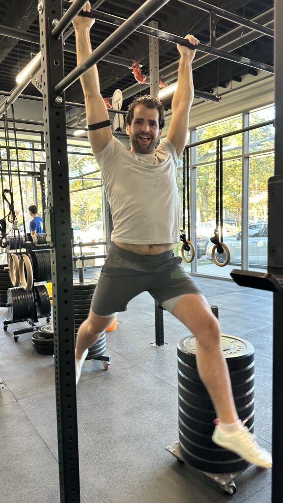 A member hanging from the pull-up bar, smiling as he hangs.