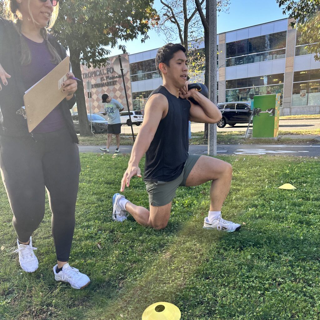 A member performing a weighted walking lunge while his judge observes his workout.