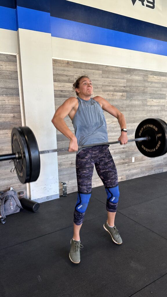 A female athlete performing a clean in the third pull position.