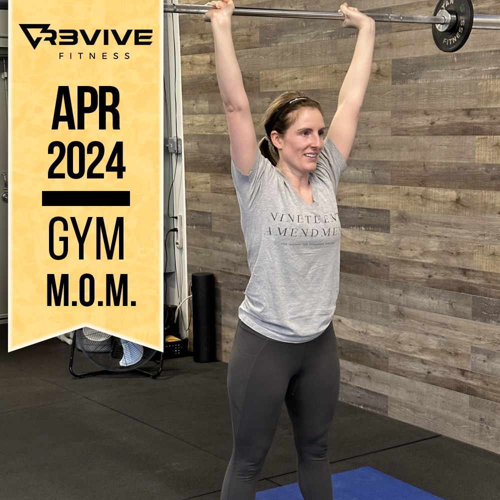 Woman lifting barbell overhead in a gym. The sign reads
