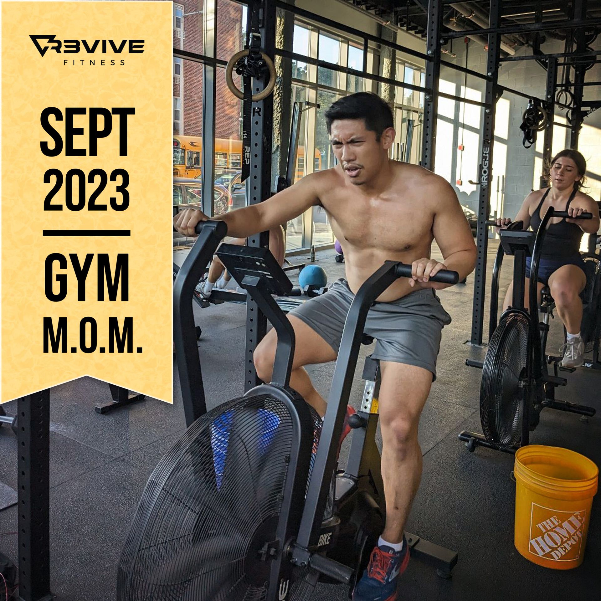 Man exercising intensely on an air bike at a gym. Others are also working out. September 2023