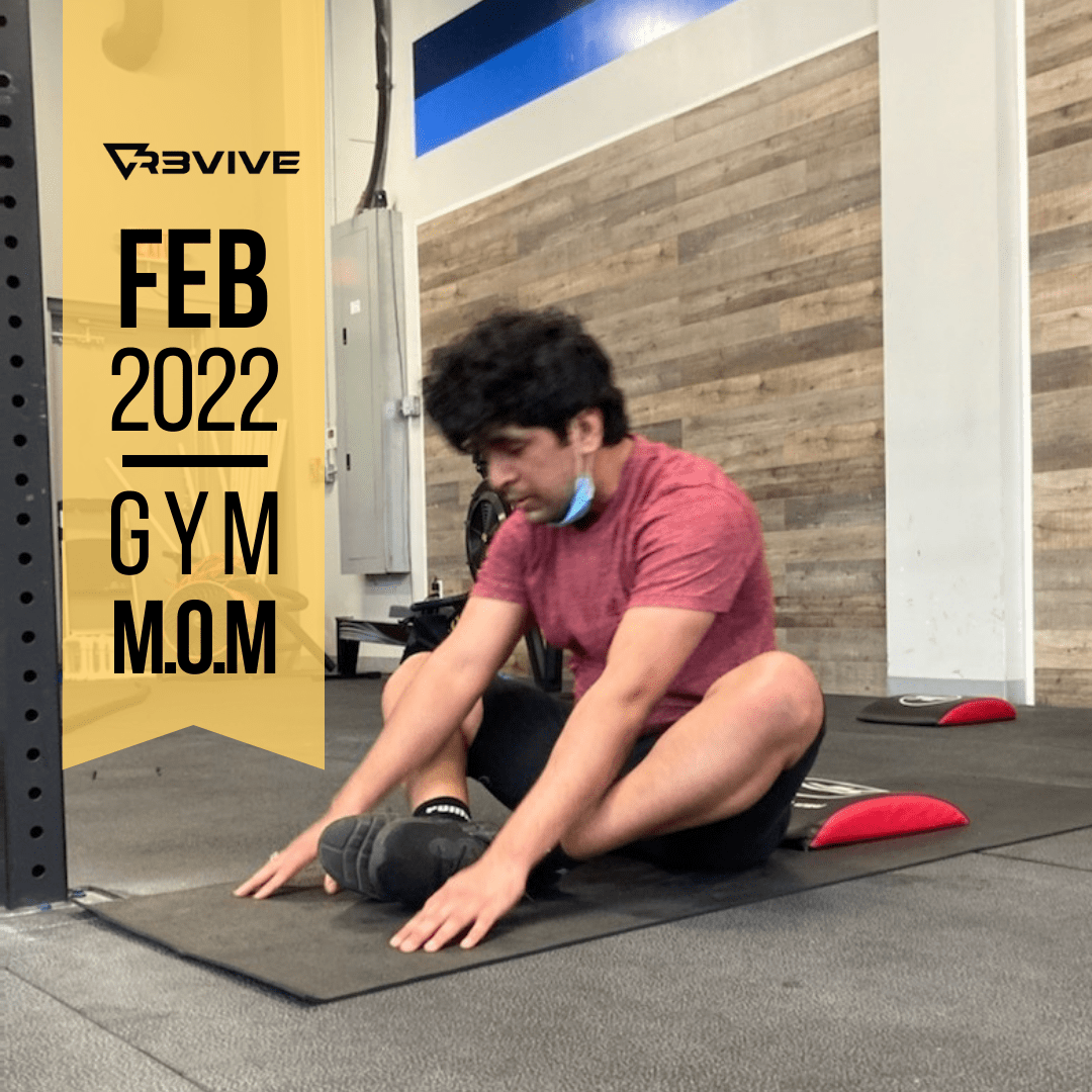 Man stretching on a mat in a gym, wearing a maroon shirt, black shorts. Gym mom Feb 2022 graphic on left.