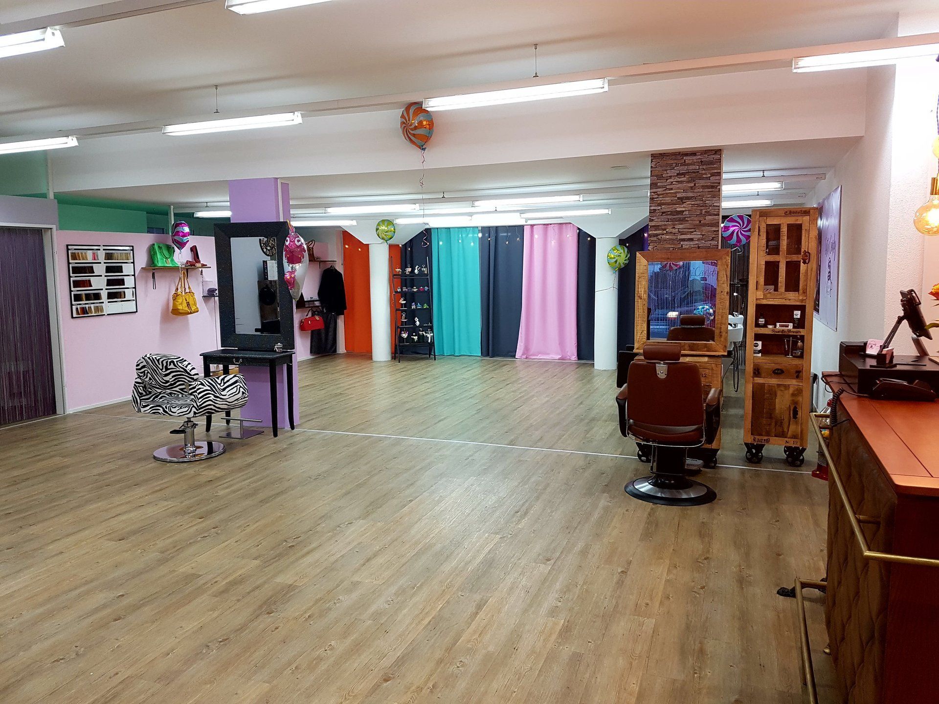 Ein großer Raum mit Holzboden und einem Friseurstuhl.