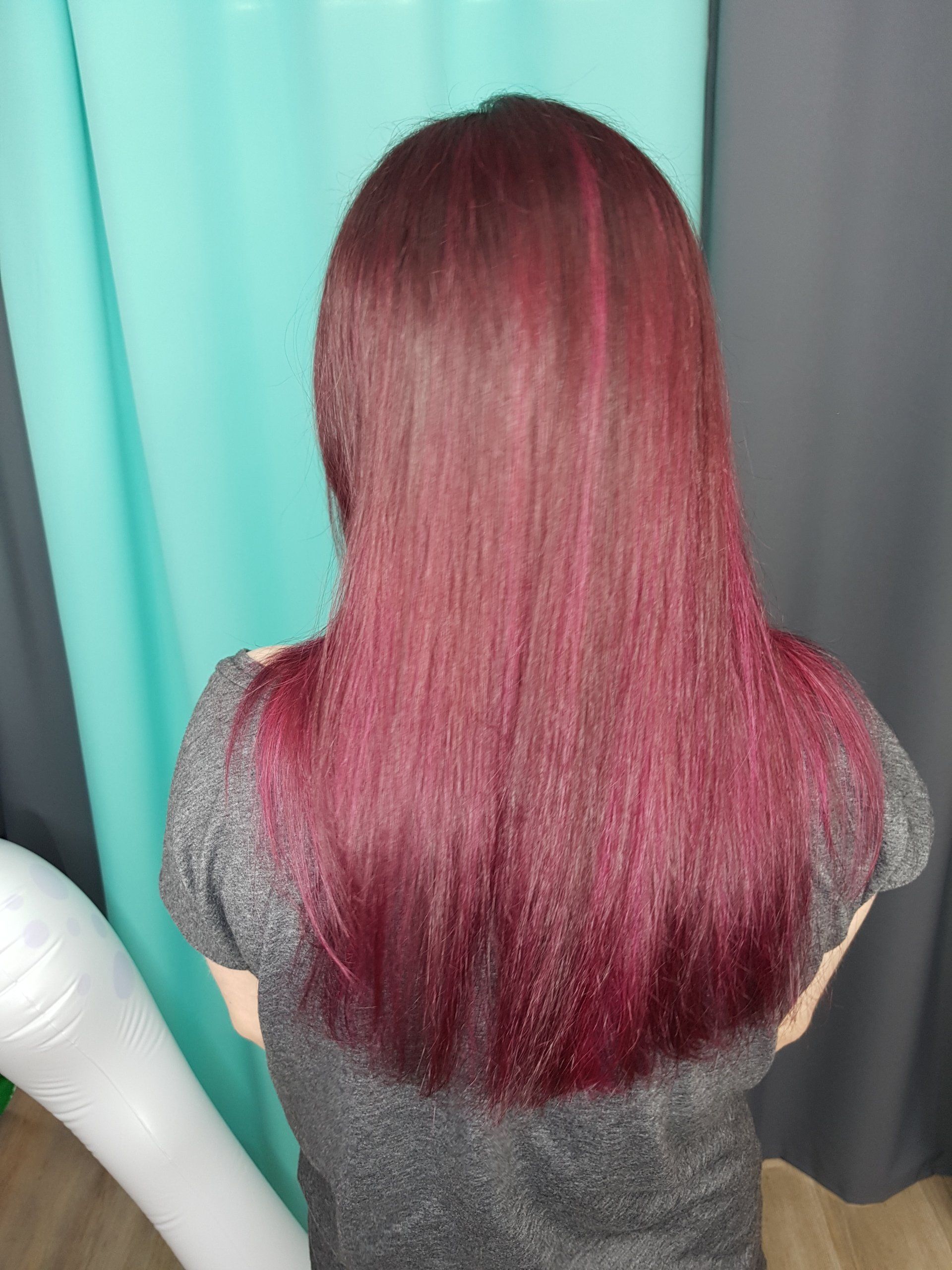 Eine Frau mit langen roten Haaren steht vor einem blauen Vorhang.