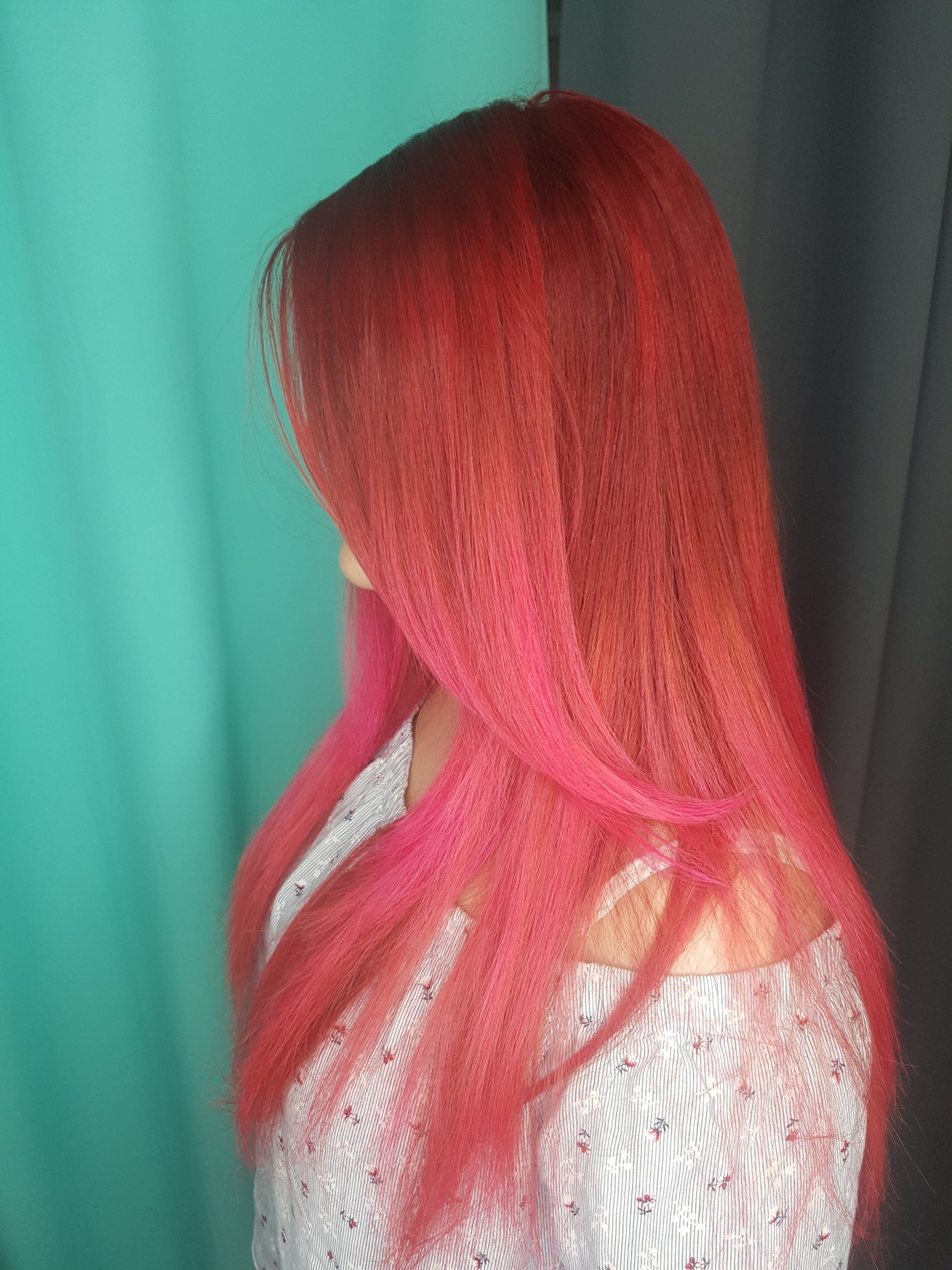 Eine Frau mit langen roten Haaren trägt ein weißes Oberteil.