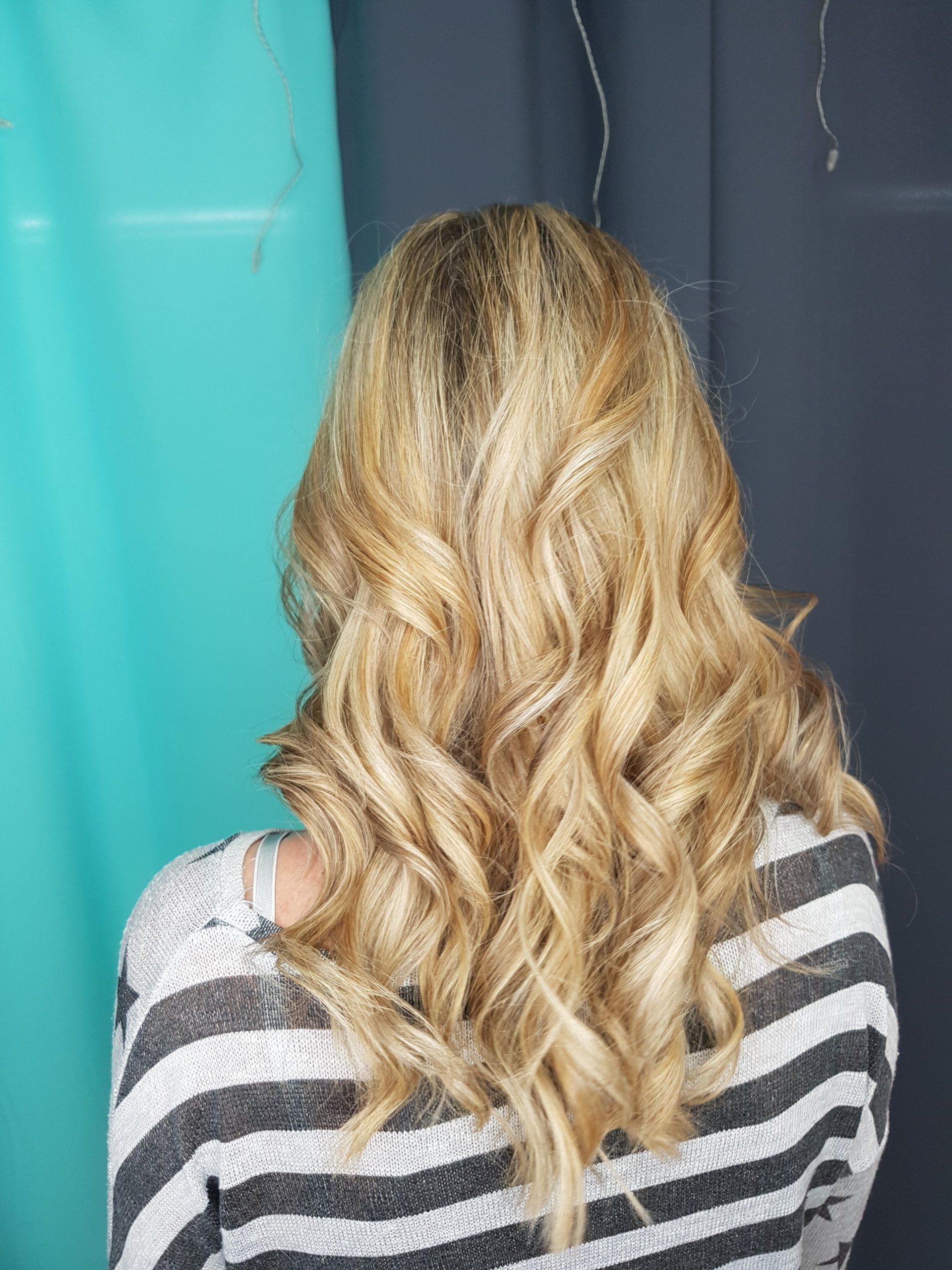 Eine Frau mit langen blonden Locken trägt einen gestreiften Pullover.