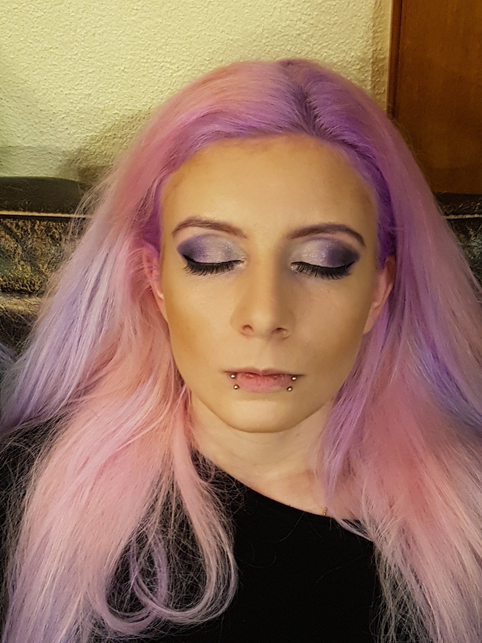Eine Frau mit rosa und violettem Haar trägt Make-up.