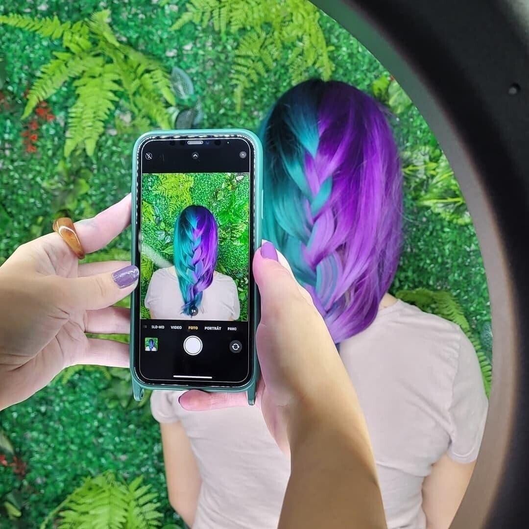 Eine Person macht ein Foto von einer Frau mit lila und blauen Haaren.