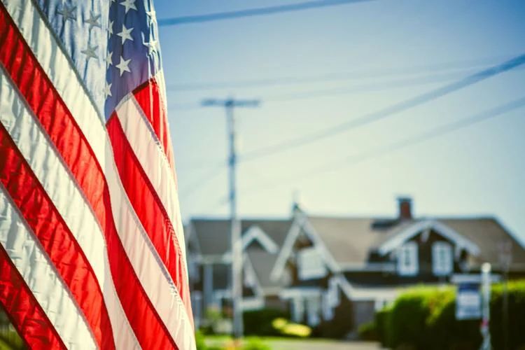 An american flag is flying in front of a house.