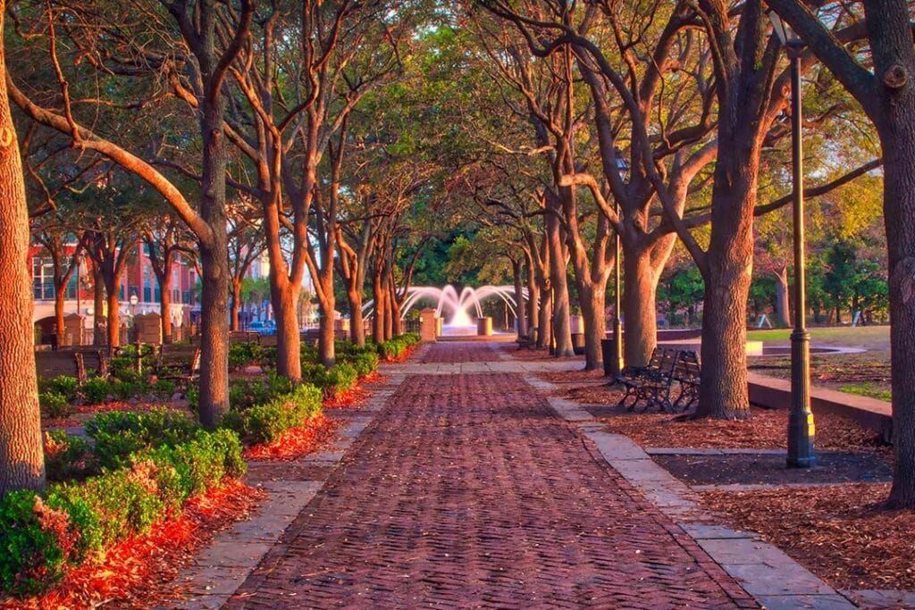 A cable-stayed bridge over water at sunset. The sky is orange and purple; the bridge is lit up.