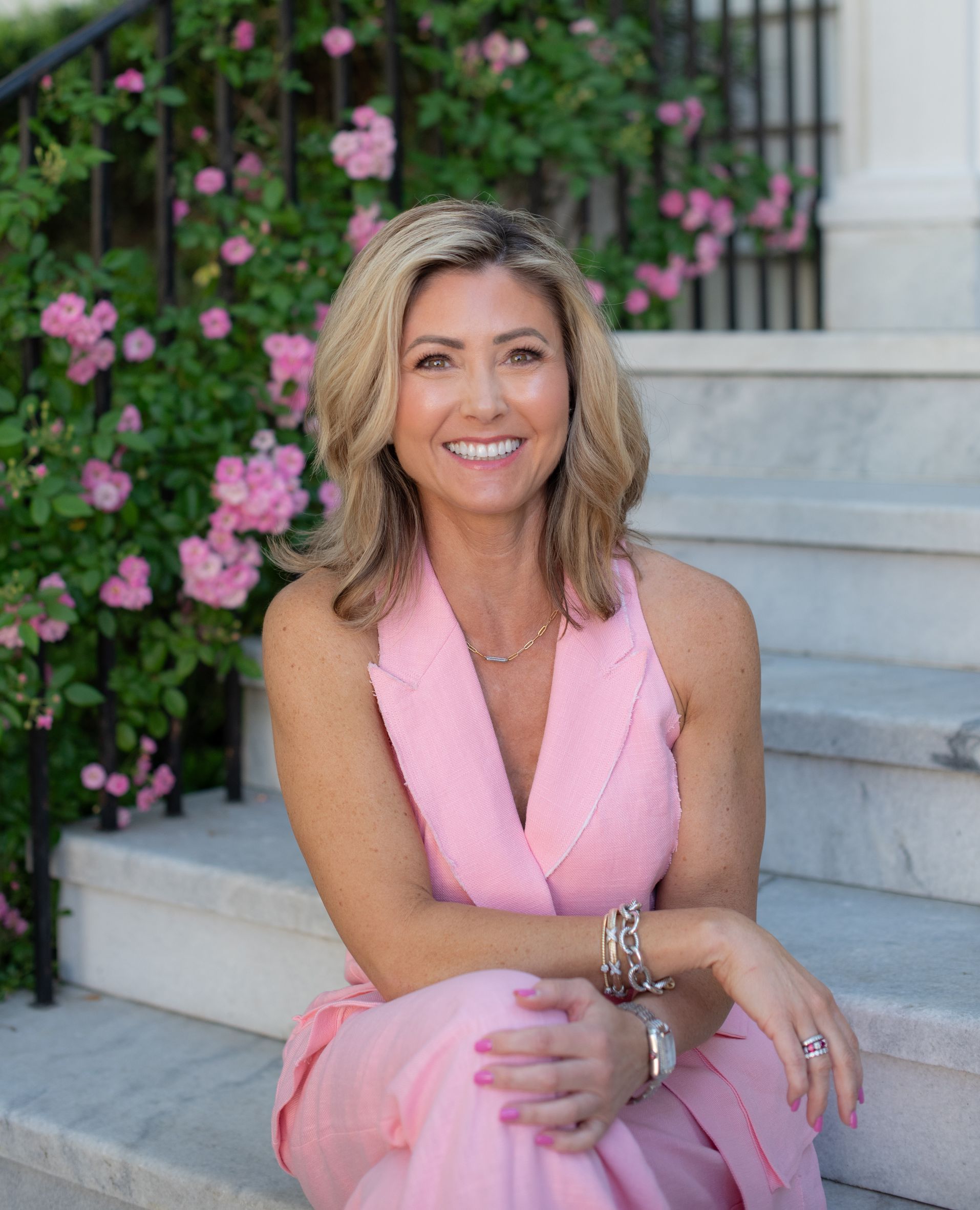 A woman in a pink dress is sitting on a set of stairs.