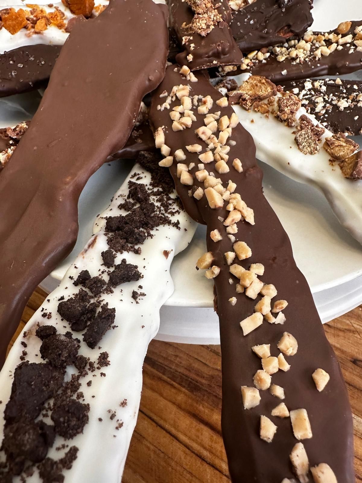Chocolate-covered pretzel rods: dark and white chocolate with various toppings like cookies and nuts.