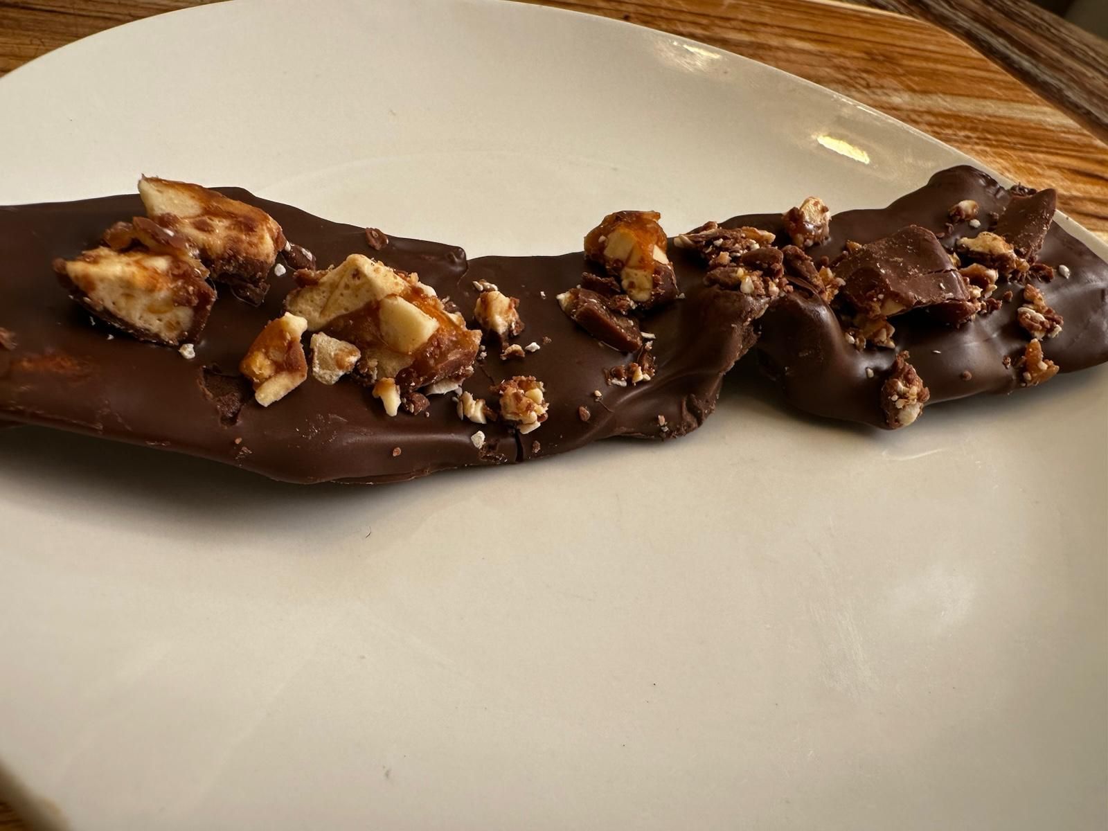 Dark chocolate bark with chopped nuts on a white plate.