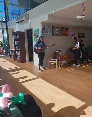 young girl singing while playing a guitar
