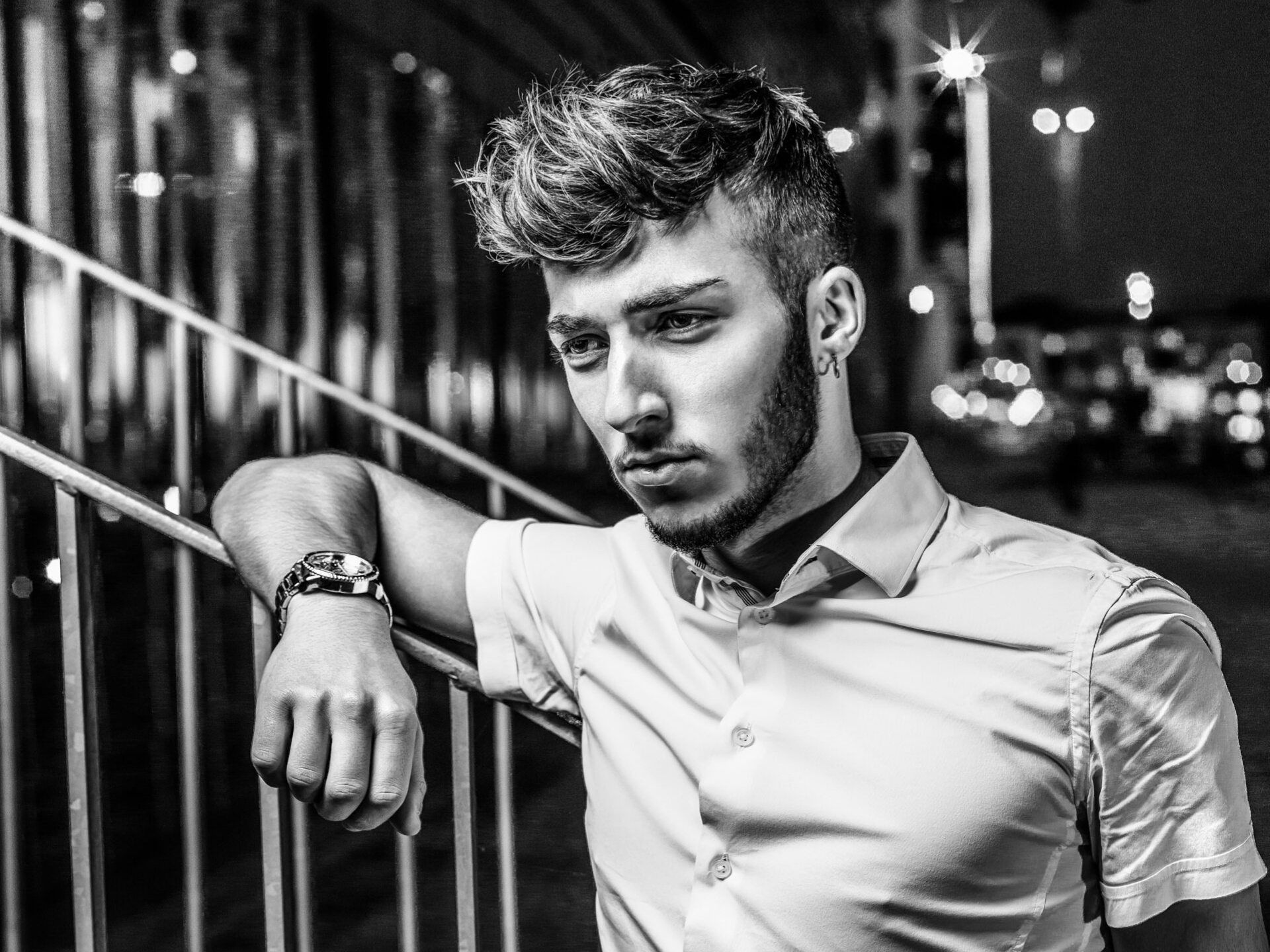 A black and white photo of a man leaning on a railing.