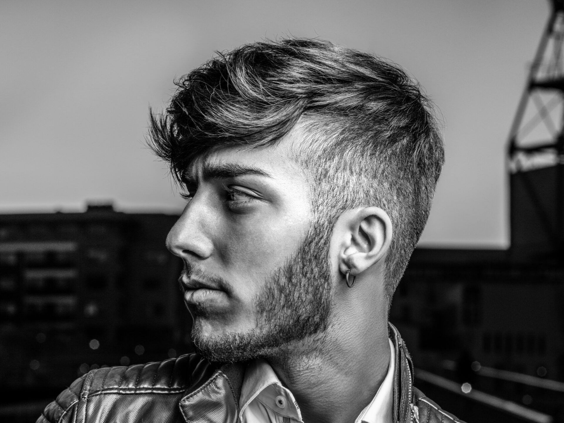 A black and white photo of a man with a beard wearing a leather jacket.