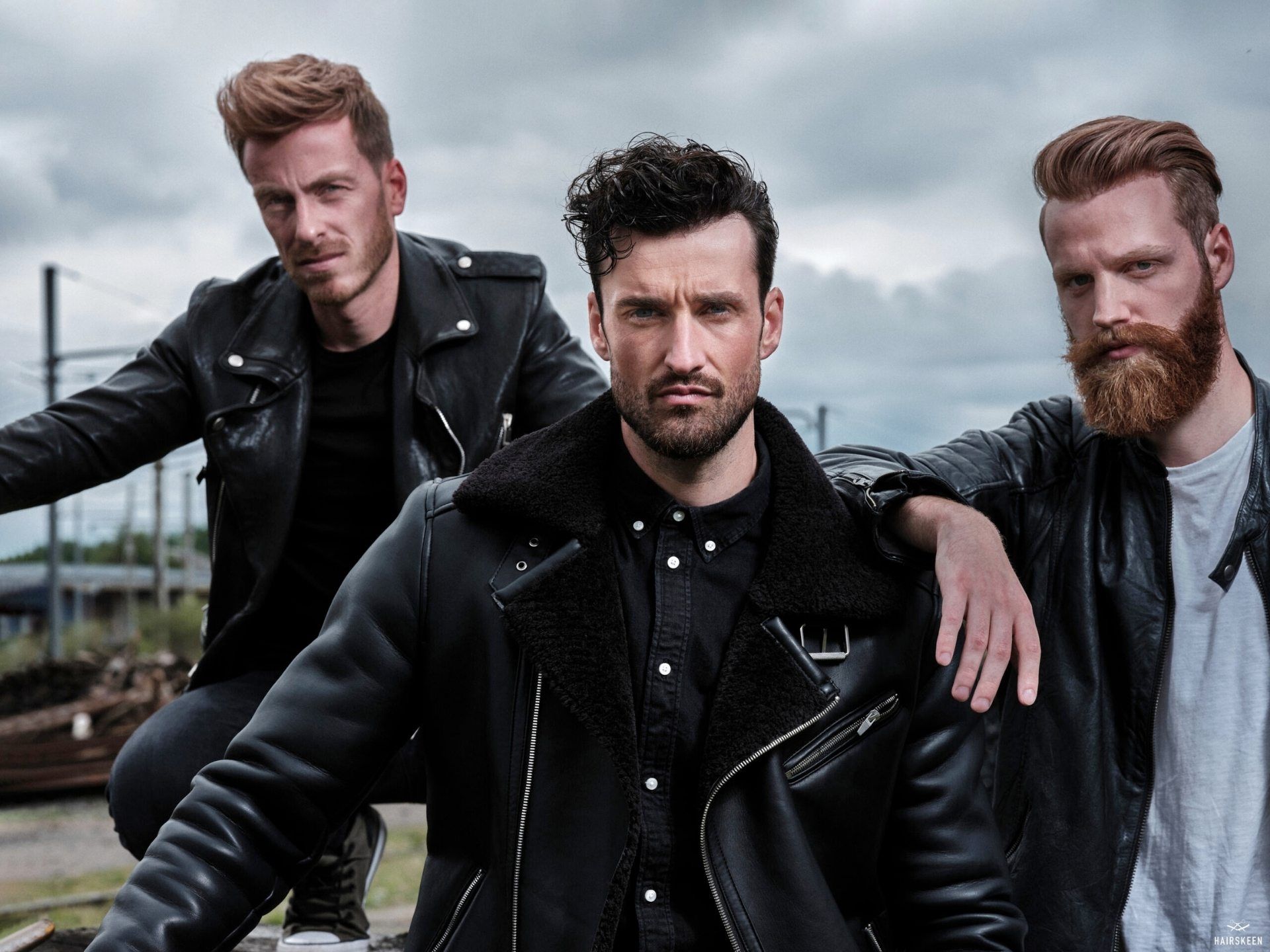 Three men wearing leather jackets are posing for a picture.