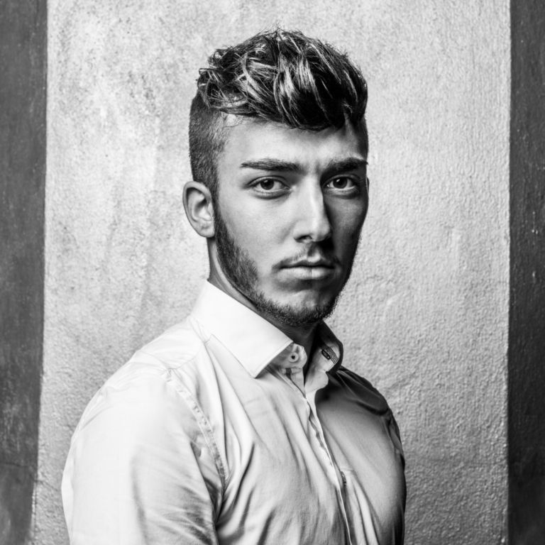 A black and white photo of a man with a beard wearing a white shirt.