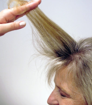 A woman is brushing her hair with a brush