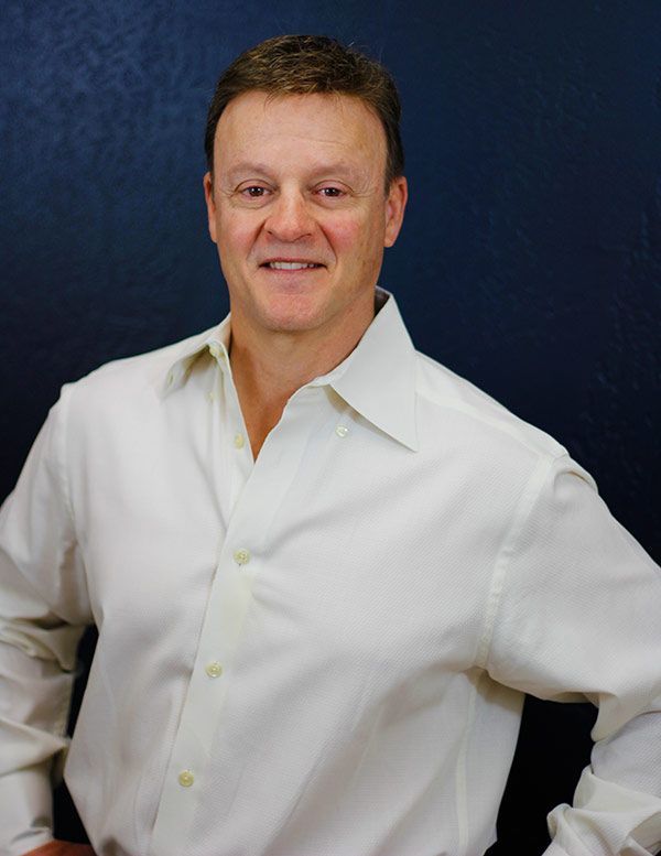 A man in a white shirt is smiling for the camera