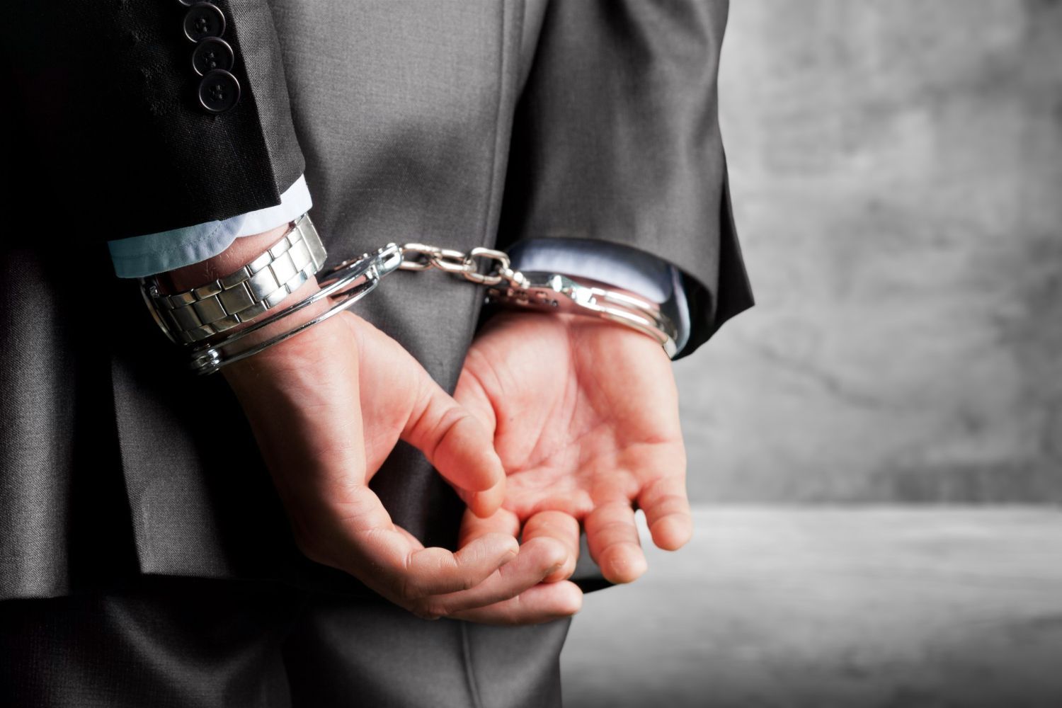 Man in suit, handcuffed behind back.
