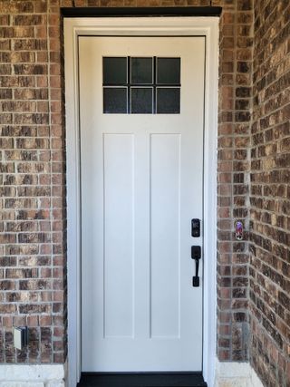 A white door with a black handle is on a brick wall.