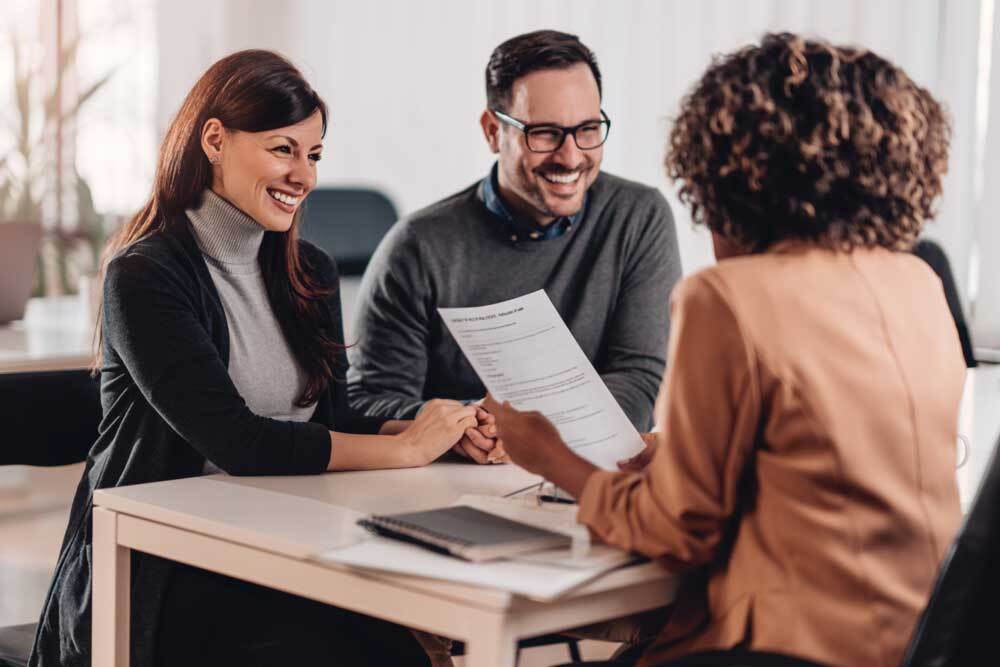 A man and a woman are sitting at a table talking to a woman.
