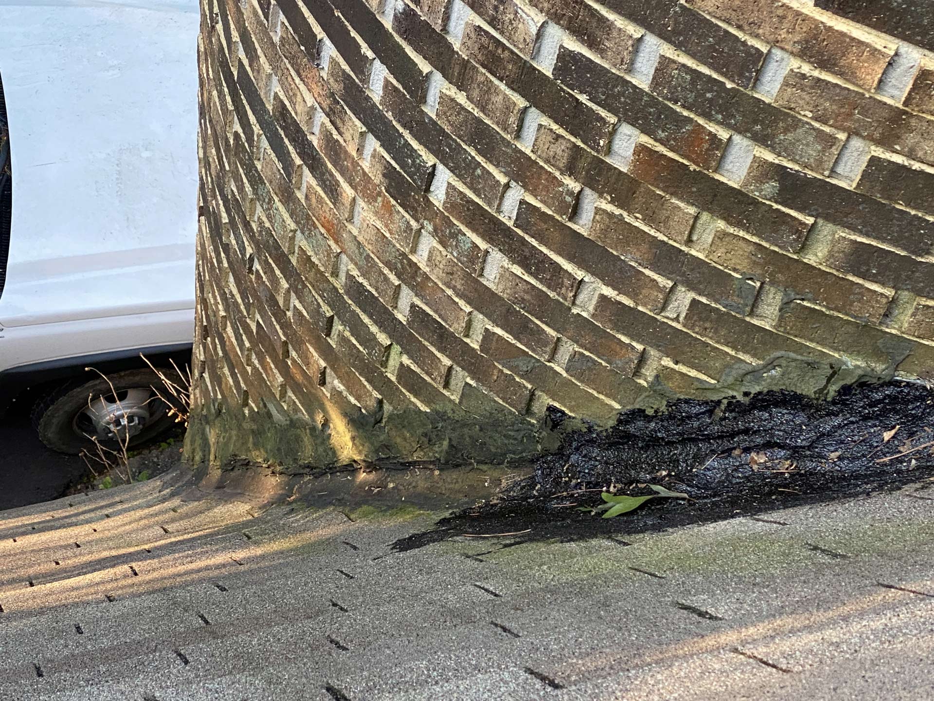 A white van is parked next to a brick wall.