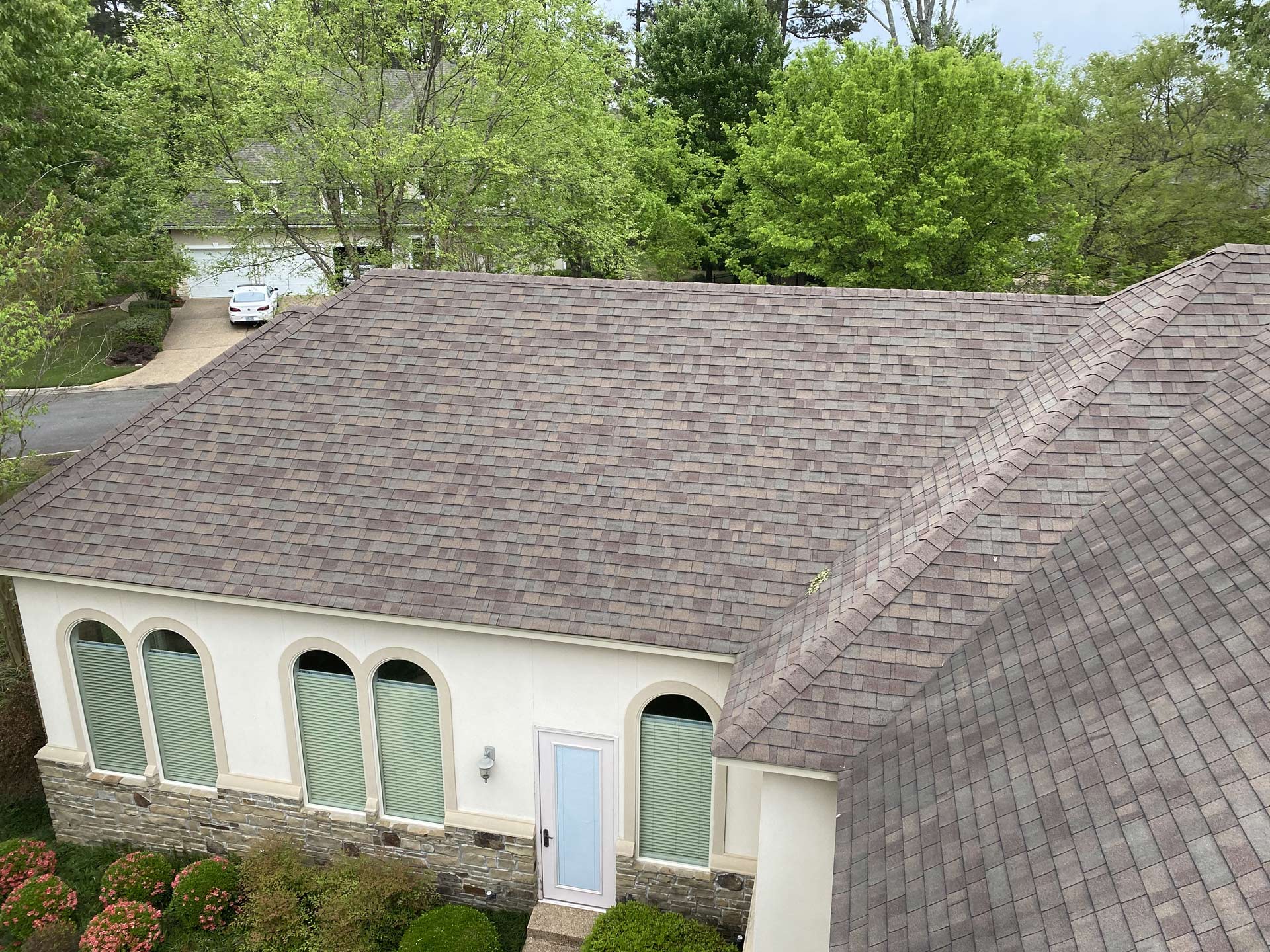 An aerial view of a house with a roof and trees in the background.