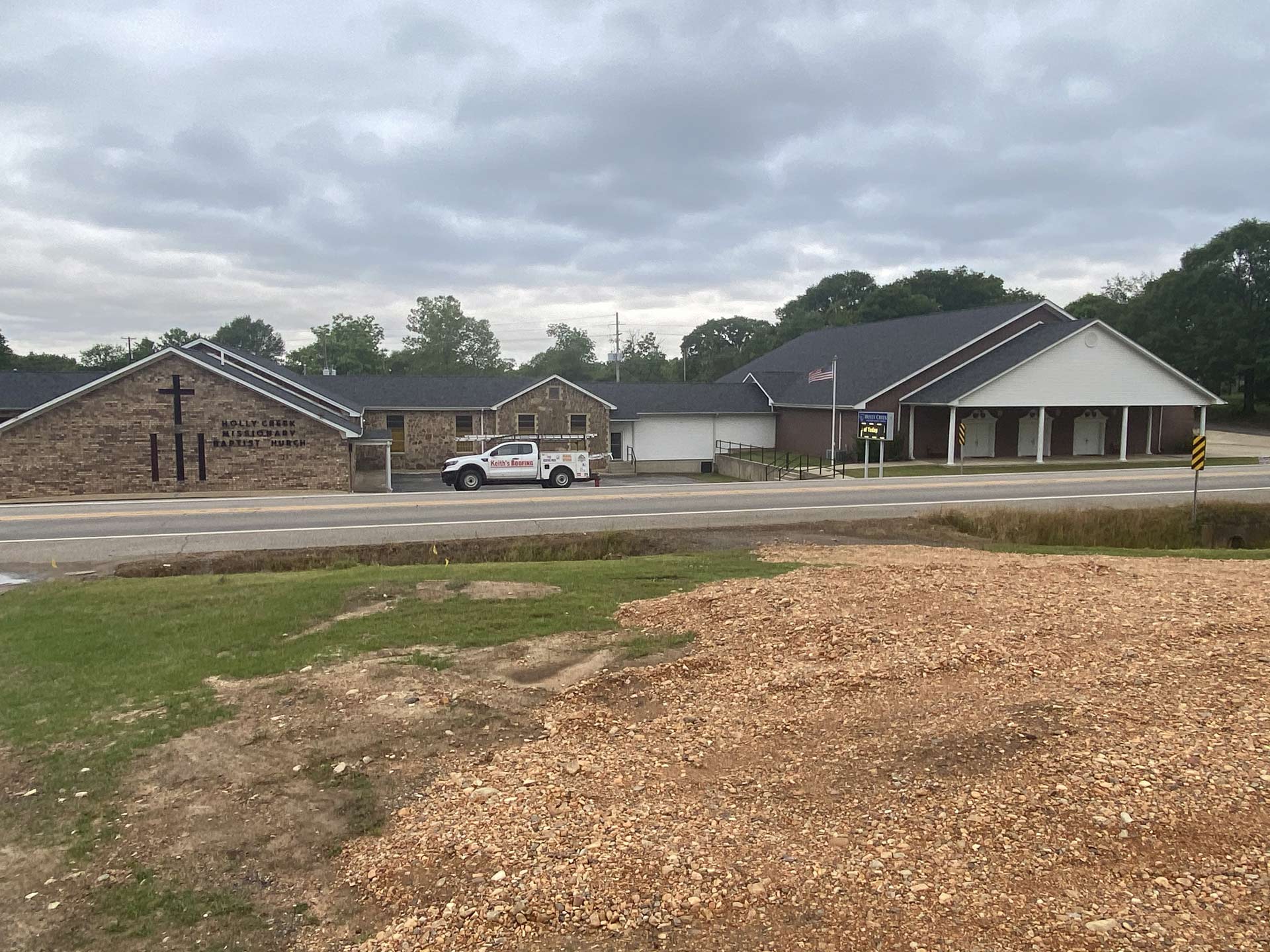 A white truck is parked in front of a brick building