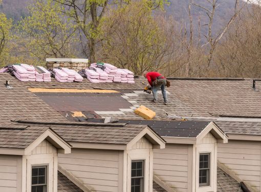 Roofing contractor in hot springs removing the old shingles from a roof ready for reroofing stock photo