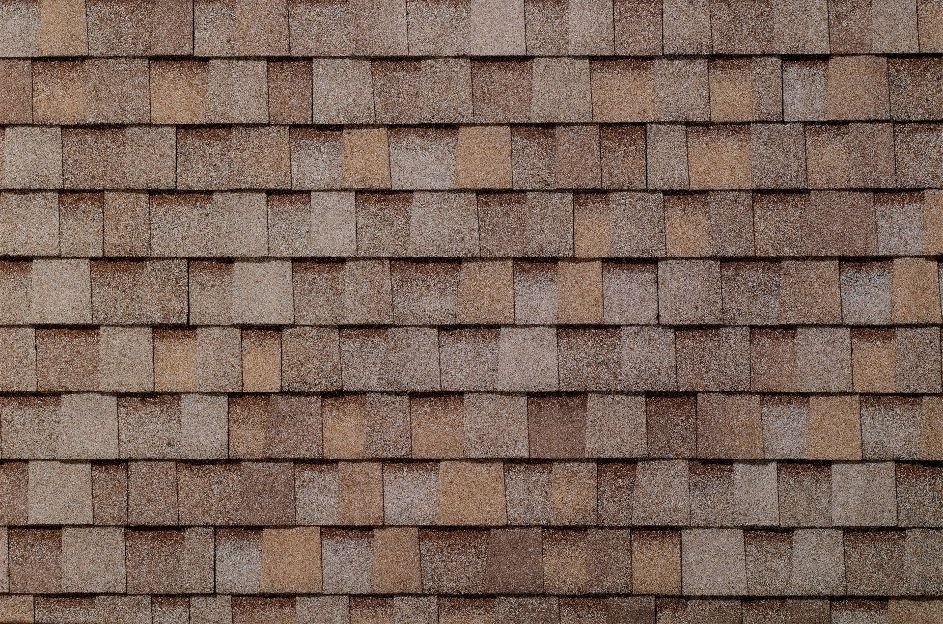 A close up of a row of brown shingles on a roof.