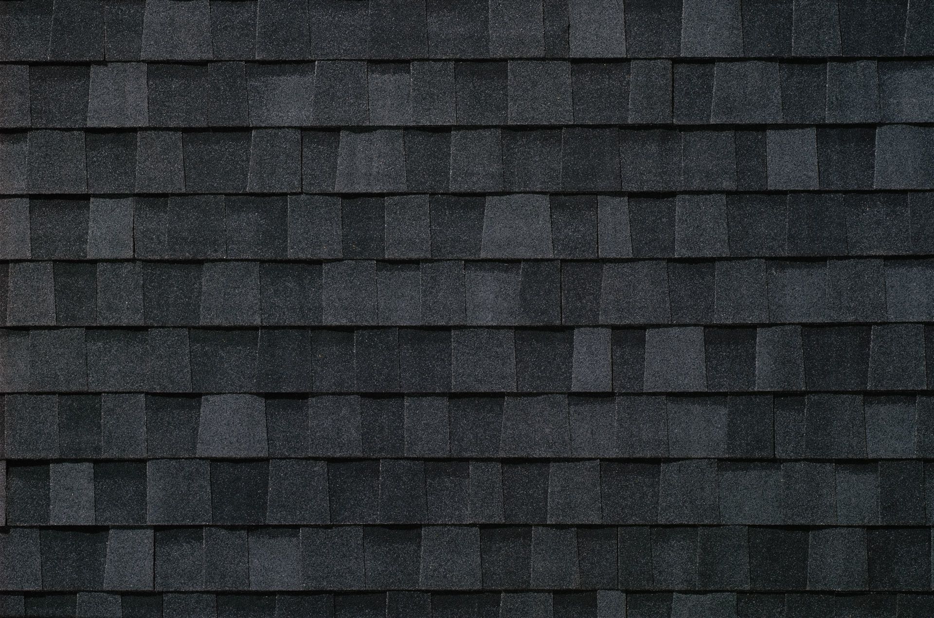 A close up of a row of black shingles on a roof.