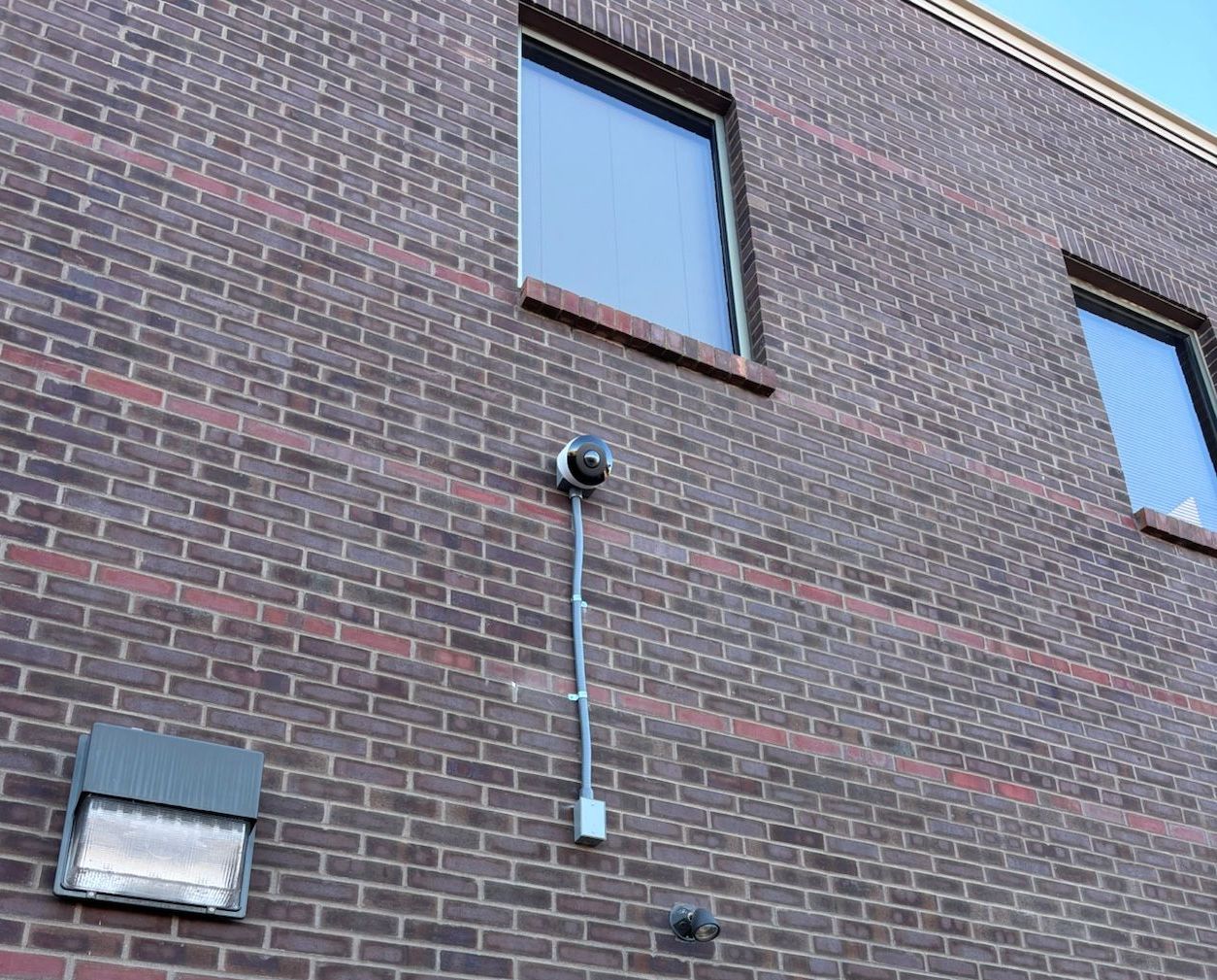 A brick building with a white door and a camera on the side.