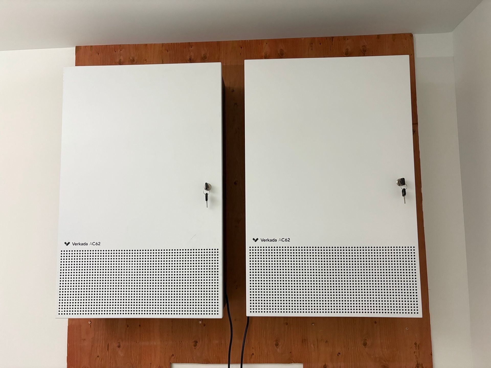 Two white cabinets are hanging on a wooden wall.