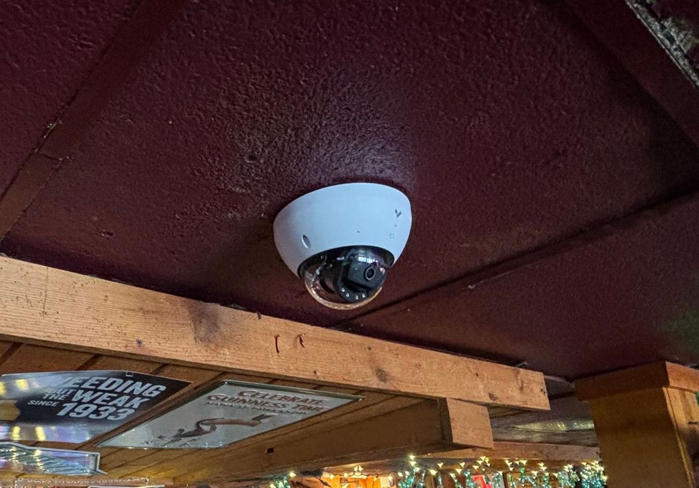 A security camera is hanging from the ceiling of a building.