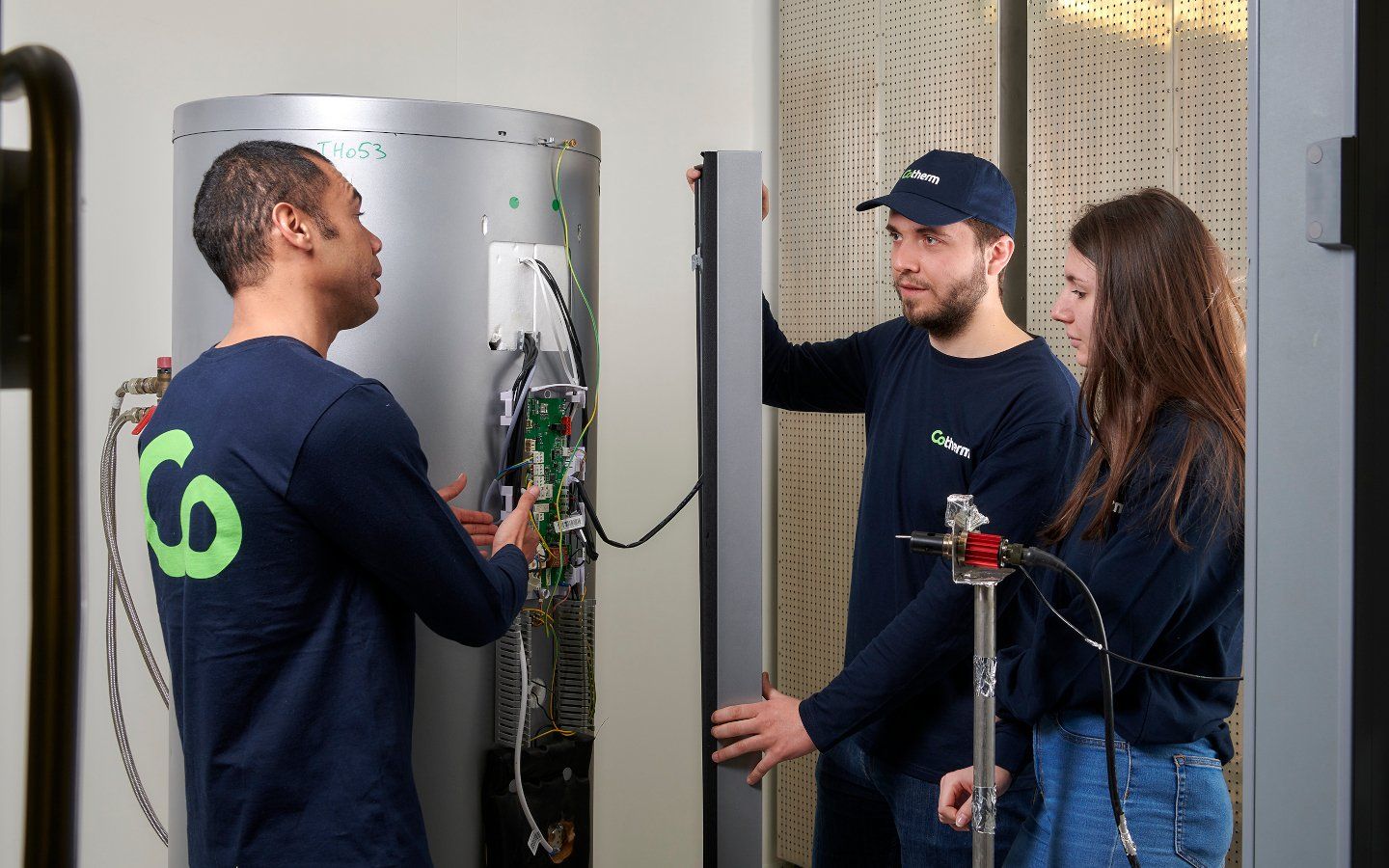 Cotherm employees inspecting a hot water cylinders thermostat and electronics