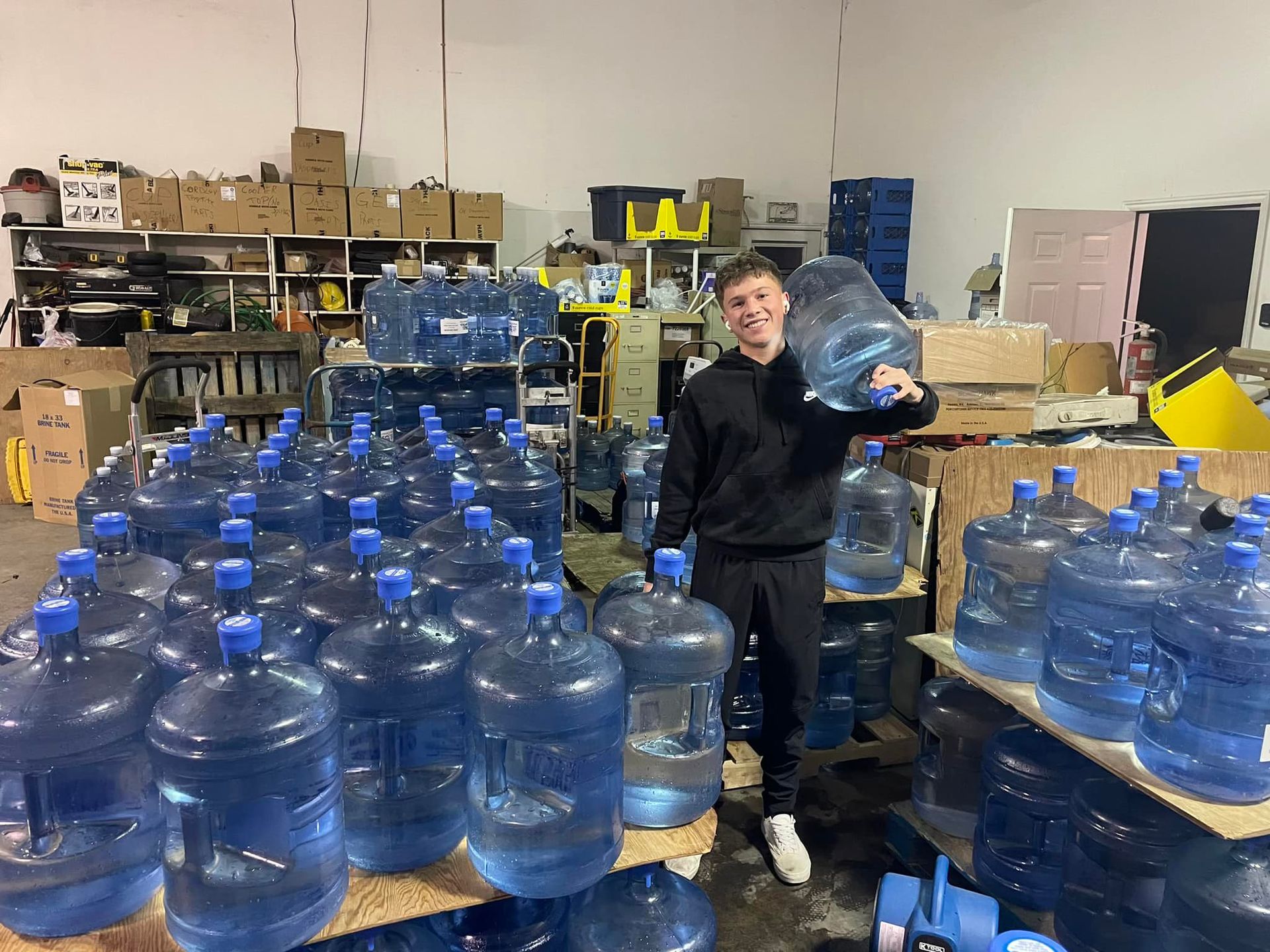 A man is standing in a room filled with lots of water bottles.