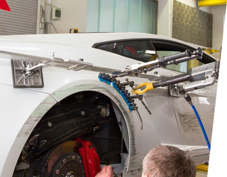 A man is working on a white sports car in a garage.